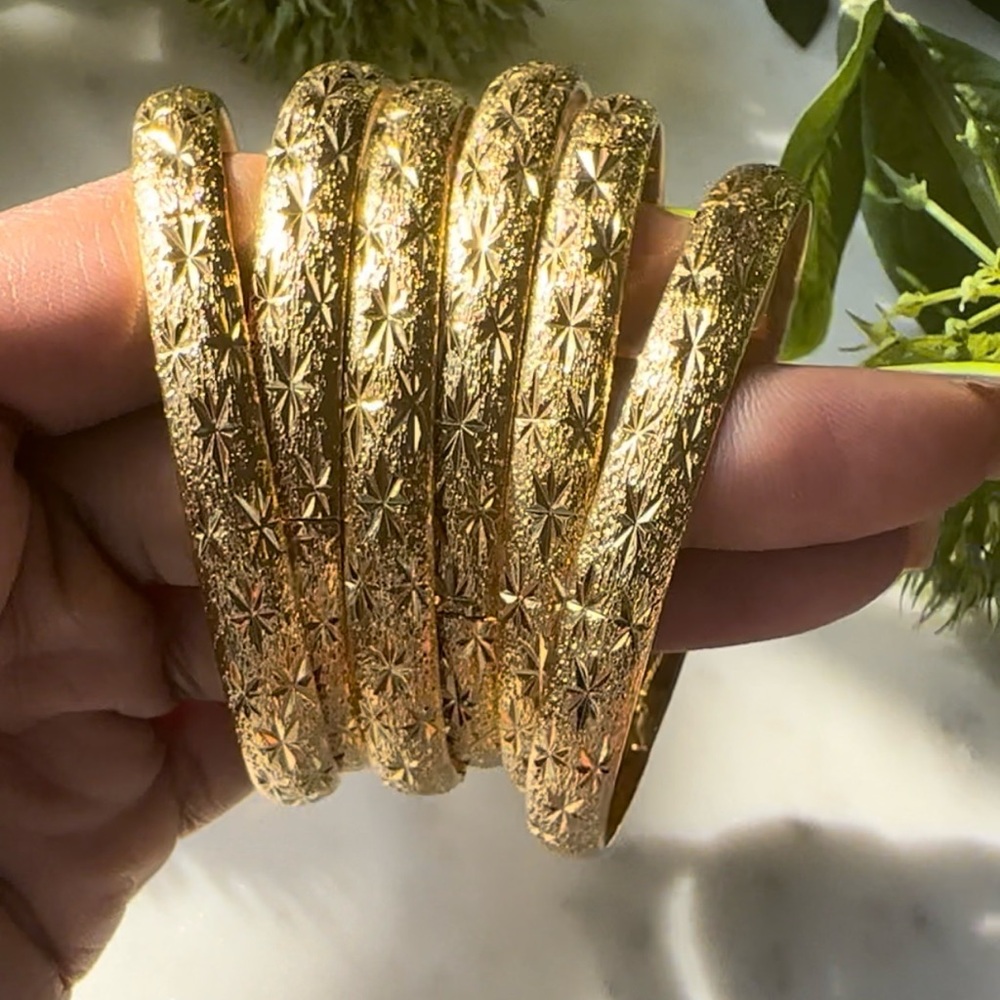 Four 24k gold plated gold bracelets.